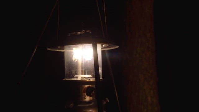 Camping lantern glowing in the dark forest