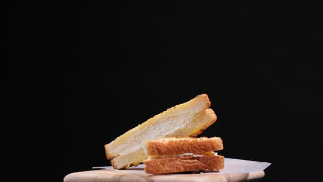 Garlic bread slices filled with cream on a wooden board
