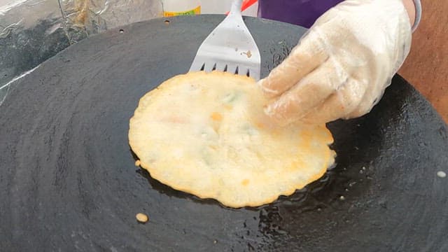 Person flipping pancakes in a hot cast iron pan