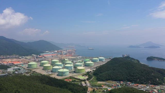 Industrial plant near the coast with green hills and ocean