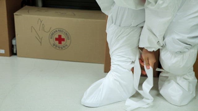 Person securing white protective gear in medical setting