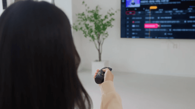 Woman operating television with remote control in bright living room