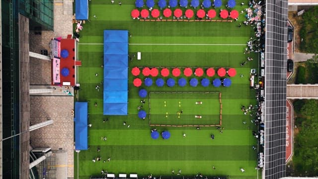 People gathered at the event venue with red and blue parasols