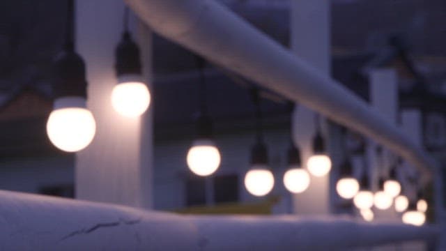 Evening street scene with a row of illuminated bulbs on a fence