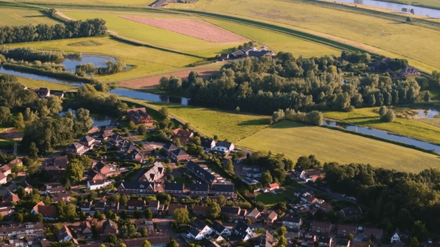 Aerial view of a village surrounded by fields and trees