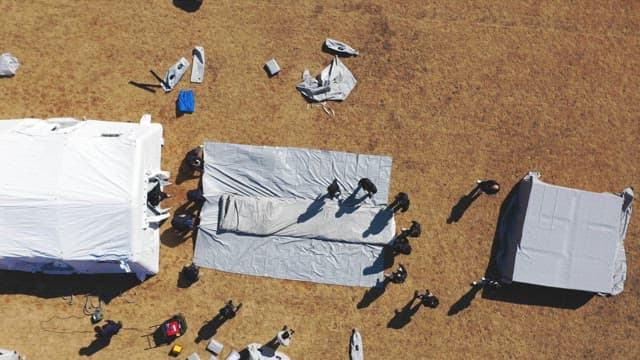 People Unfolding Large Tarps on Ground