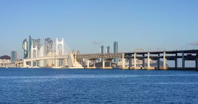 From morning to night view of a bustling port city Busan with tall skyscrapers and Gwangan Bridge