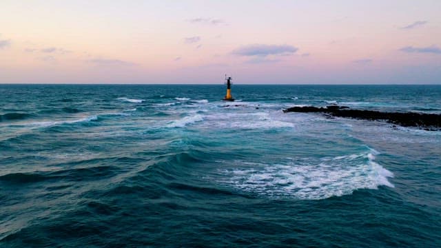 Waves Crashing Near a Coastal Beacon at Dusk
