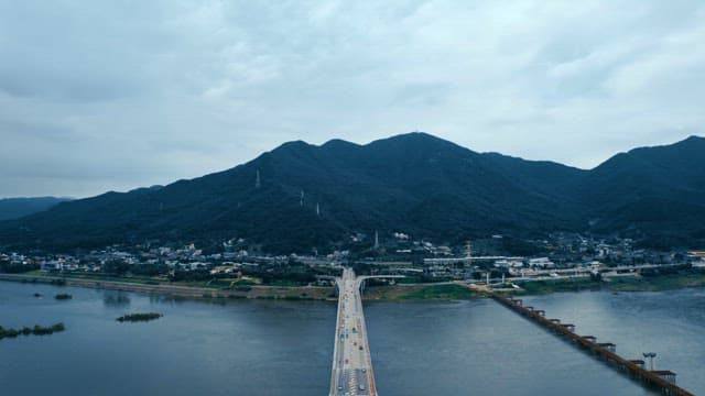Bridge crossing a wide river with mountains