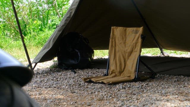 Setting up camping equipment under a tent near greenery