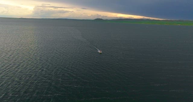 Boat sailing on a vast sea at sunset