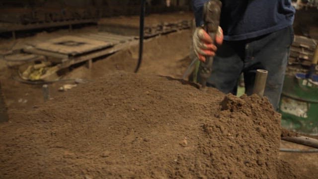 Worker using a tool to compact soil