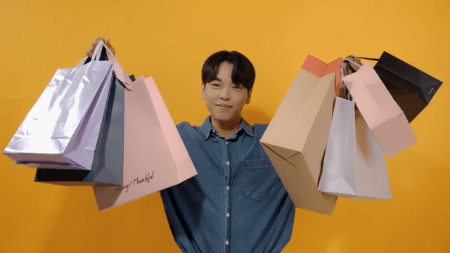 Happy man smiling while holding several shopping bags