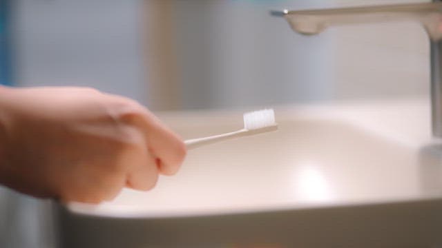 Preparing a toothbrush with toothpaste at a sink