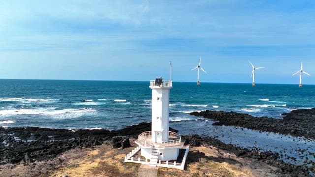 Lighthouse and wind turbines by the sea