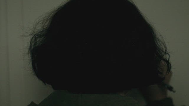 Person leaving a note on the wall of a dark room