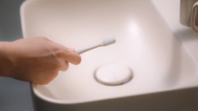 Preparing a toothbrush with toothpaste at a sink