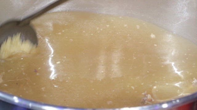 Stirring chicken soup in a large pot