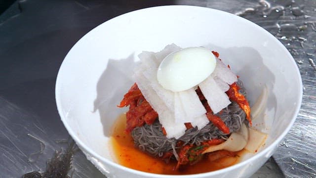 Putting sliced cucumbers in cold buckwheat noodles with raw pollack