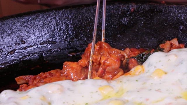 Person picking up hot spicy stir-fried chicken with chopsticks