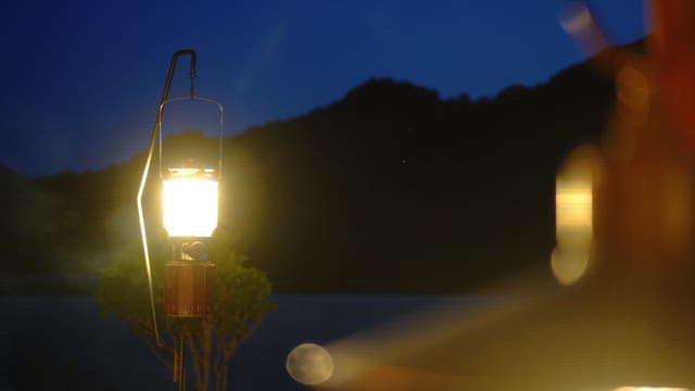 Lantern glowing at night with mountains in the background