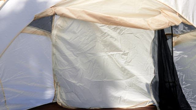 Opening a tent set up against a backdrop of greenery