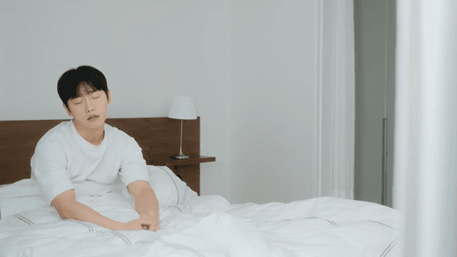 Man waking up and stretching in bed 