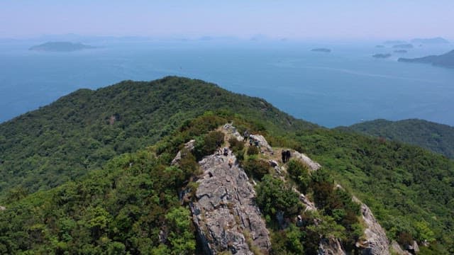 Group of hikers atop a lush mountain overlooking the sea