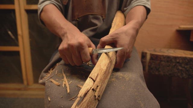 Person carving wood indoors