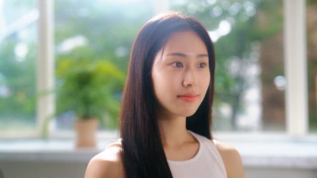 Woman combing her hair with a comb in a sunny room