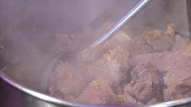Cooked pork backbones in a ladle