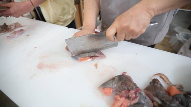 Preparing and slicing fresh fish on the cutting board in the kitchen