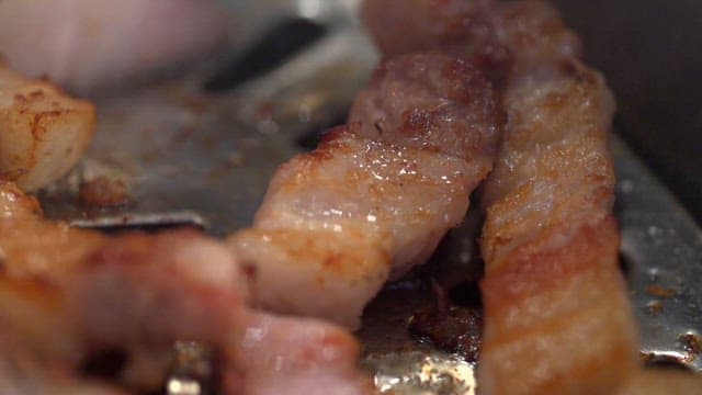 Grilled pork belly sizzling on a grill