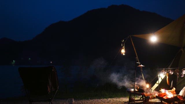 Campsite with lights on the lakeside under the dark night sky