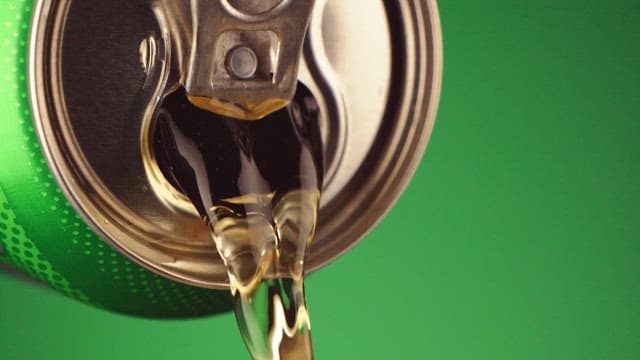 Beverage pouring from a can on a green background