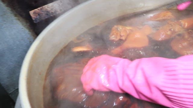 Pig's feet cooked in brown broth in a large pot in the kitchen