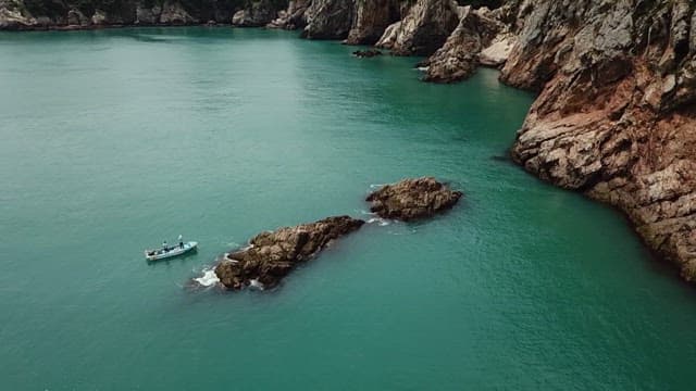 Two people boating around rocky coastal waters