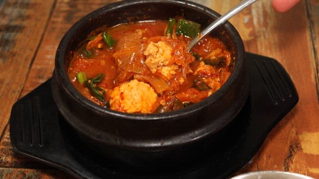 Savory Korean kimchi stew served hot in a stone bowl and rice