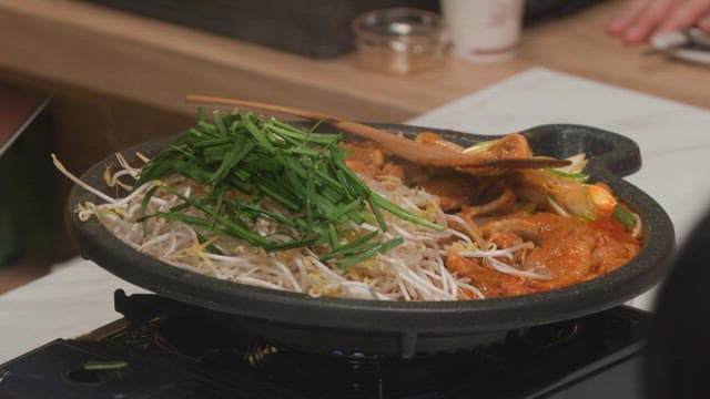 Cooking stir-fried spicy pork with bean sprouts and chives in a kitchen