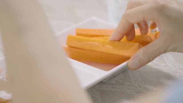 Hand reaching for carrot sticks on a plate