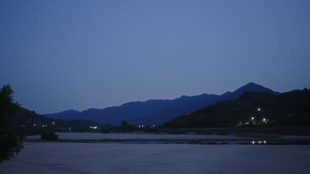 Mountains and plains as night falls, lights begin to glow