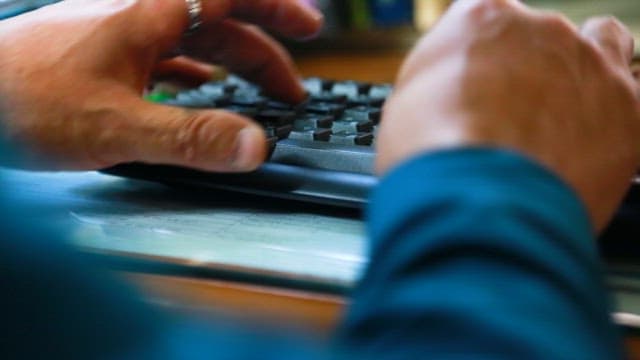 Hands Typing on a Keyboard on the Work Desk