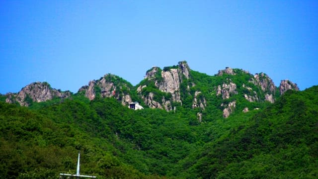Lush green rocky mountains under clear and blue skies