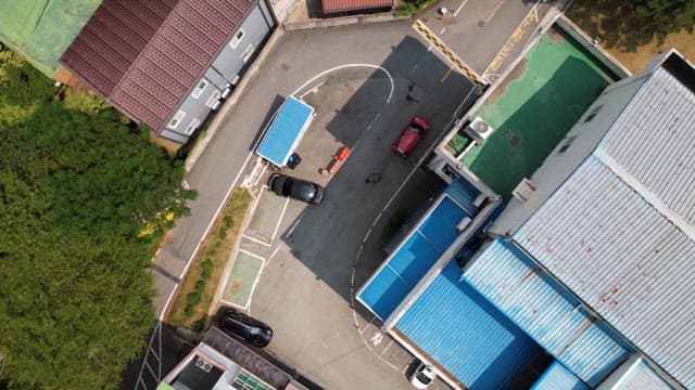 Red car driving through a narrow road between the buildings of a town