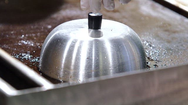 Cheeseburger patty cooking on a grill
