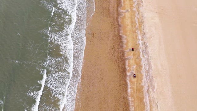 People Driving ATVs on a Vast Beach under Cloudy Sky