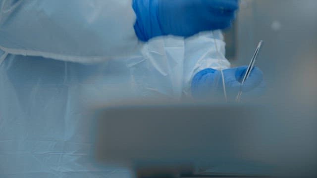 Autopsy doctor wearing surgical gowns and using medical equipment in an autopsy room