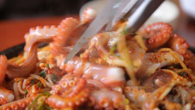 Spicy seasoned braised octopus cooking on a hot plate