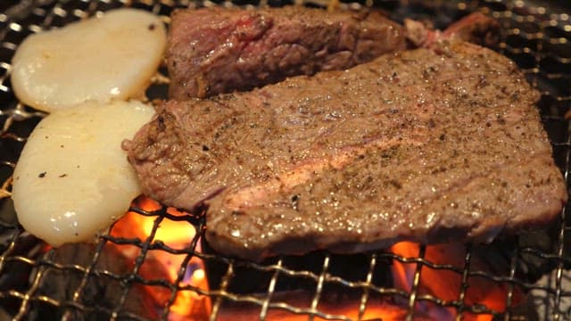 Grilled steak and onions over charcoal fire