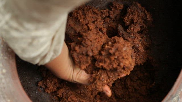 Lump of traditional Korean soybean paste scooped out by hand from a jar